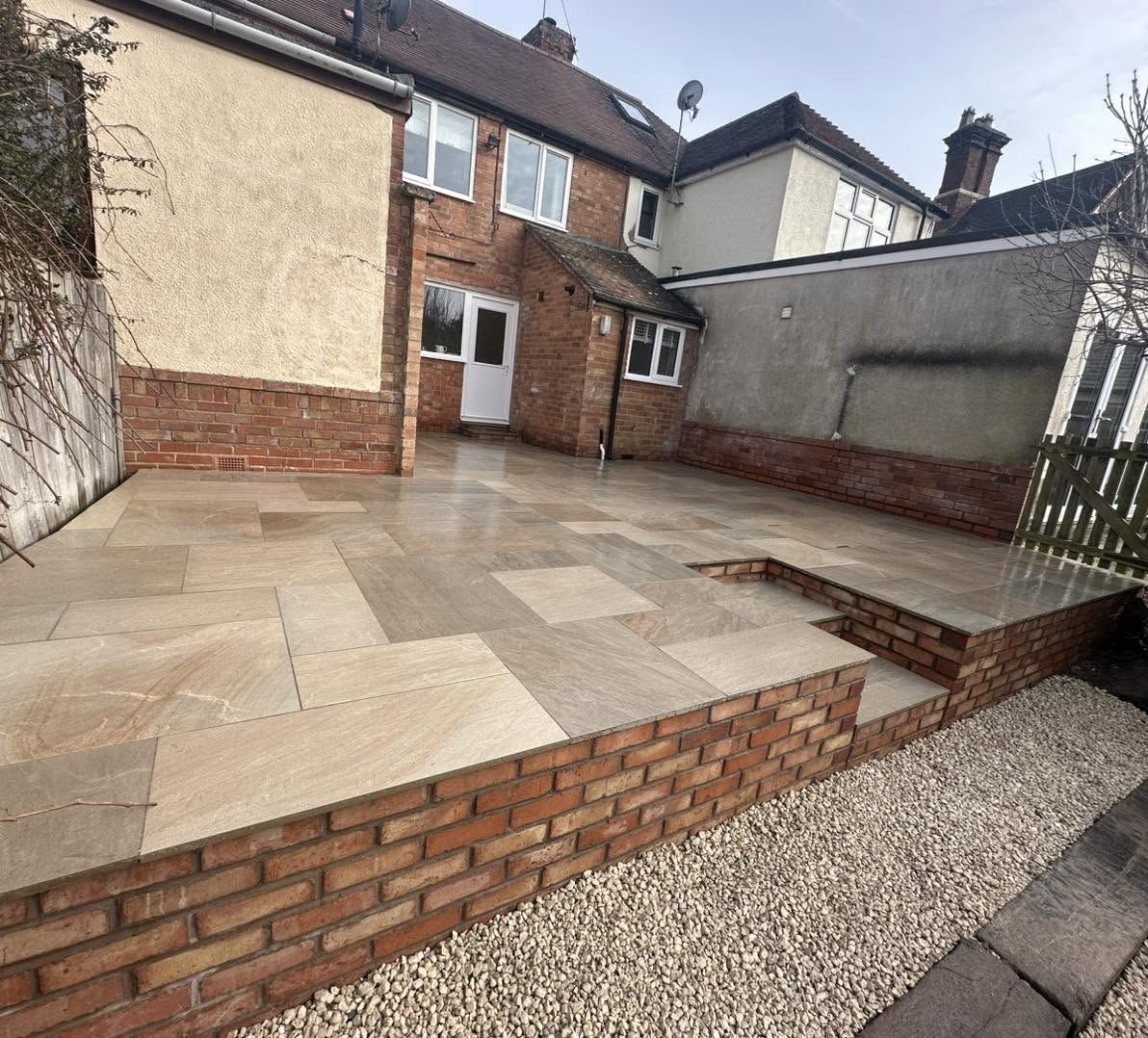 Raised sandstone patio with brick wall